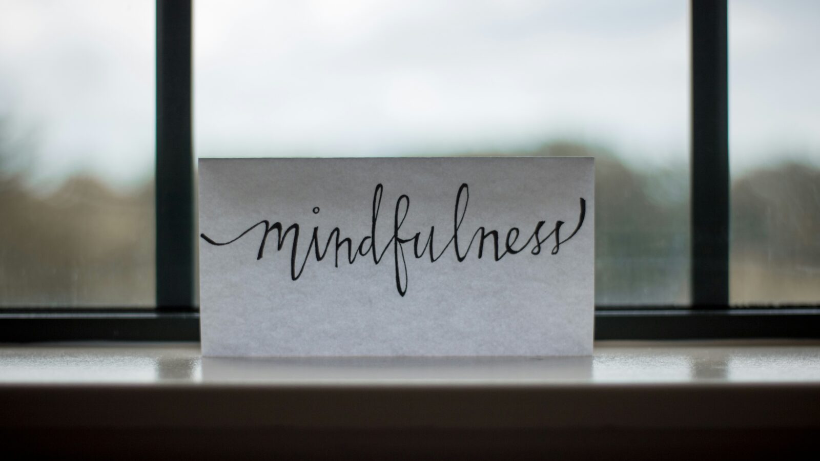 A white sheet of paper with mindfulness written on it by a window