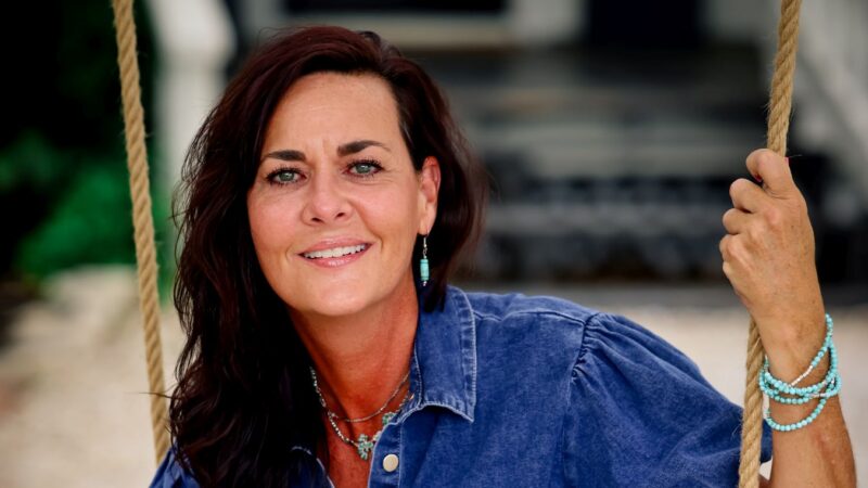 Leadership performance strategist Beth Jones, founder of the HEAL framework, wearing denim dress and sitting on a swing