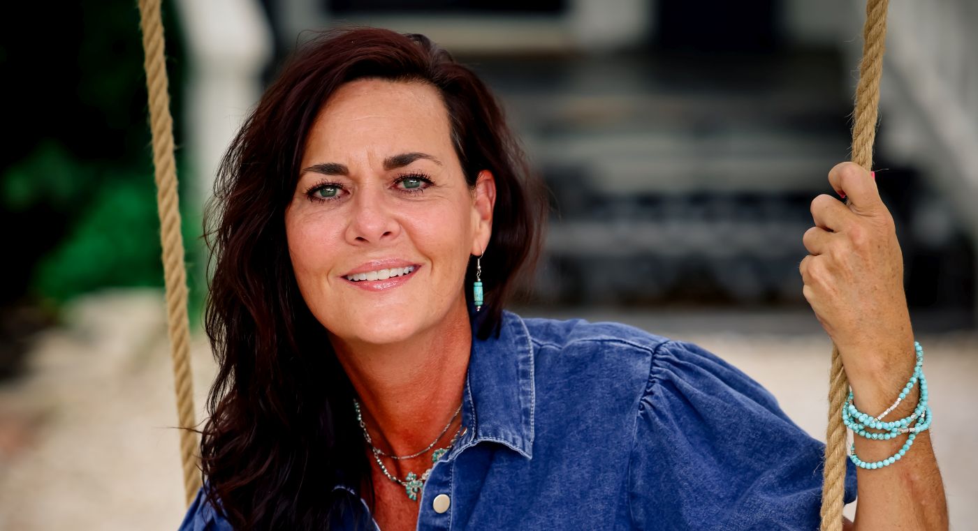 Leadership performance strategist Beth Jones, founder of the HEAL framework, wearing denim dress and sitting on a swing