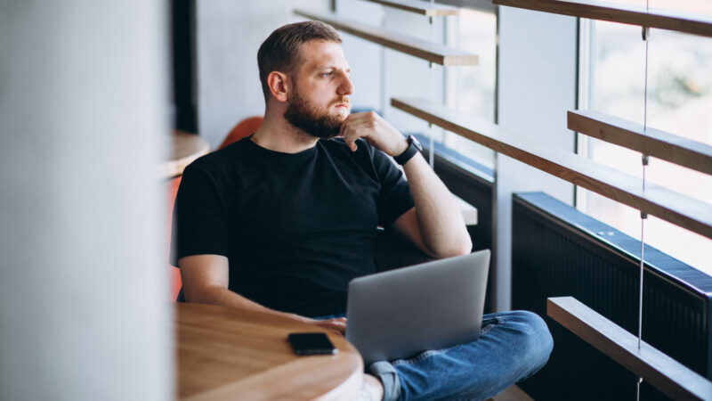 A leader sitting beside a window with a laptop, reflecting on the human impact of AI at work.